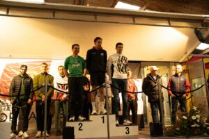 Podium masculin : le vainqueur en veste noire sur la marche 1, le deuxième en maillot vert IPP Pré-en-Pail, le troisième en veste blanche et or.